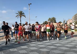 Los participantes en el reto, con Pitufollow a la cabeza, recorren el paseo de la Playa del Postiguet.