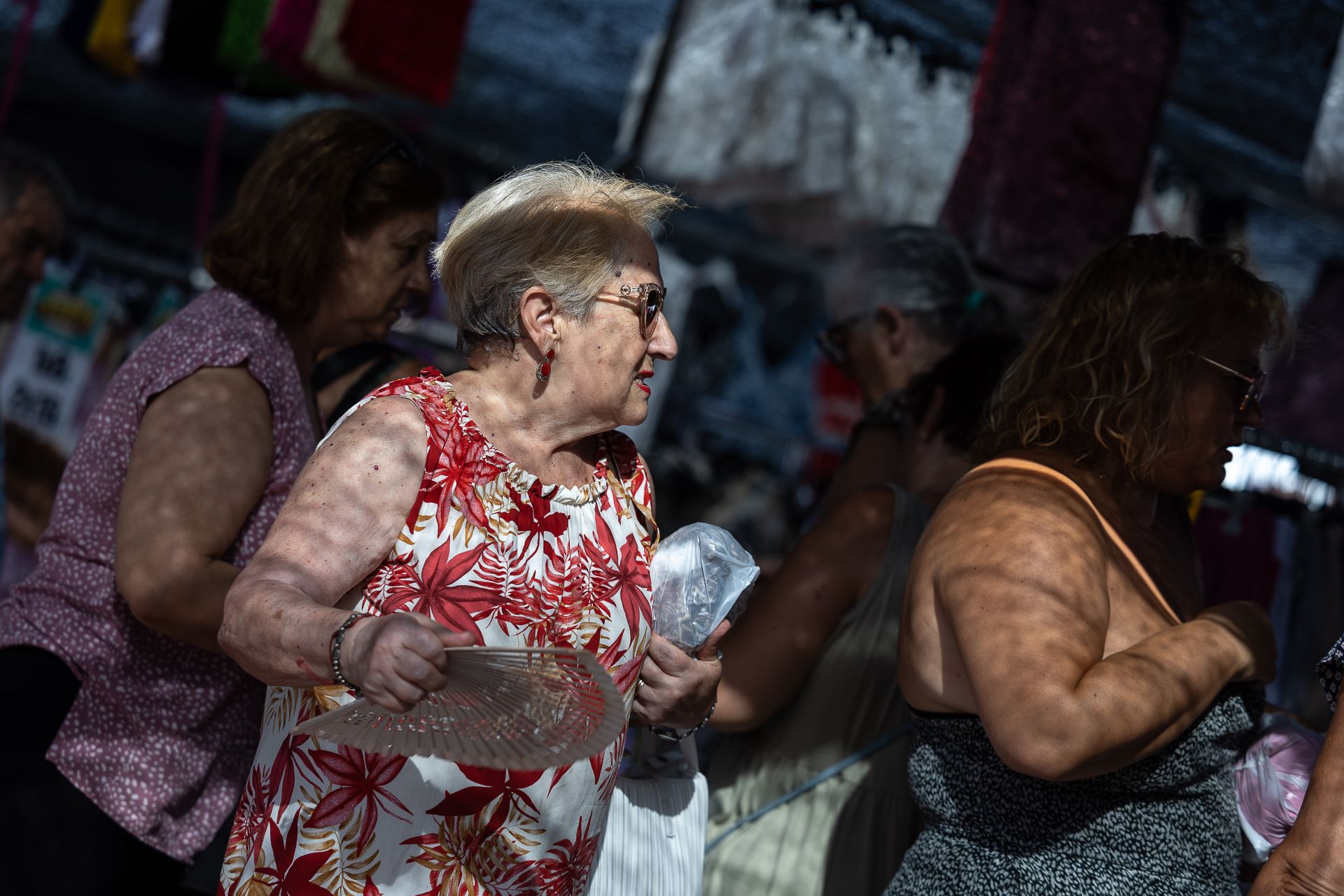 Una mujer se protege del calor con un abanico.
