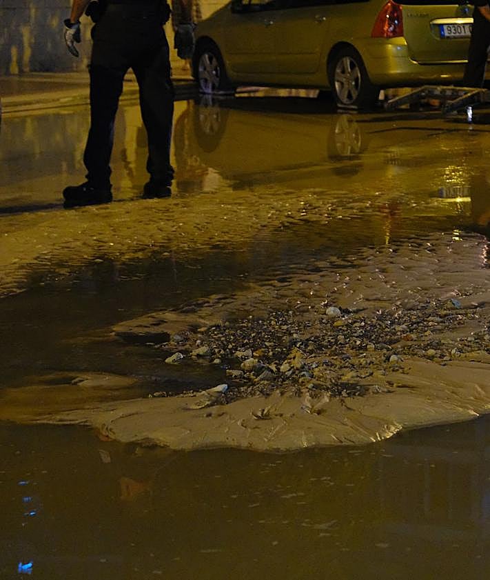 Imagen secundaria 2 - 1. Un bombero comprueba la profundidad del socavón. 2. Tratan de sacar el vehículo atascado. 3. Restos en la calle de las aguas fecales.