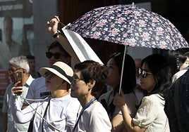 Varios turistas se protegen del calor.
