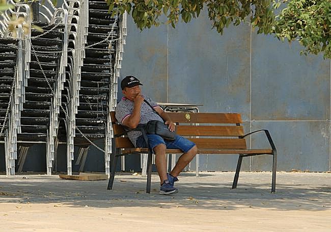 Una persona se refugia a la sombra del calor.