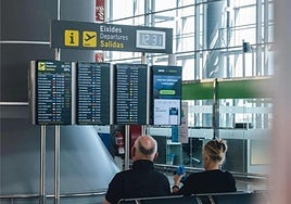 Dos turistas miran el panel de vuelos.