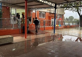 Una madre lleva a brazos a su hijo en un colegio de Dénia durante un día de lluvias.