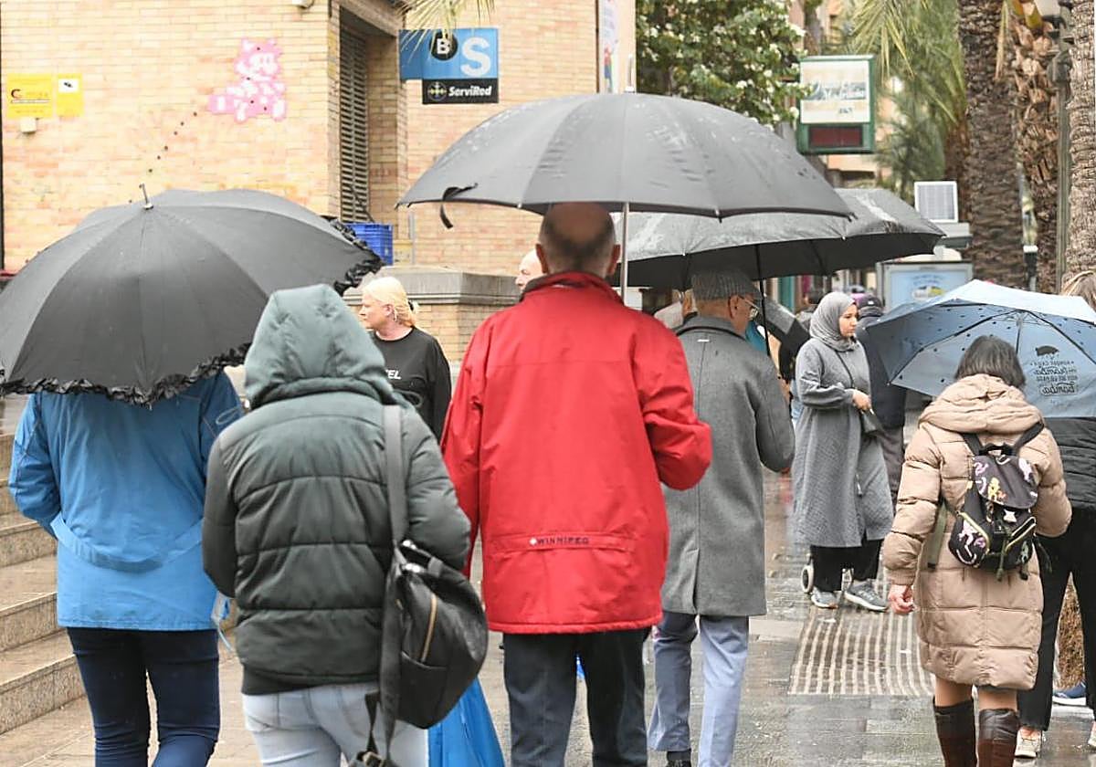 Personas con paraguas en los alrededores del Mercado Central.