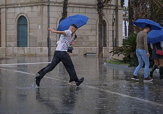 Varias personas se protegen de la lluvia en Alicante.