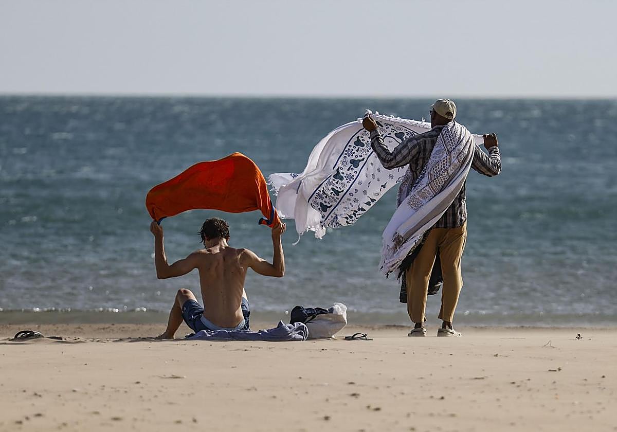 Una pareja recoge sus pertenencias de la playa por el viento.