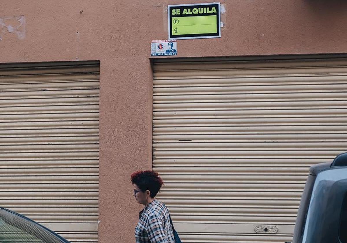 Una mujer pasa por debajo de un cartel de 'Se Alquila' en Alicante.