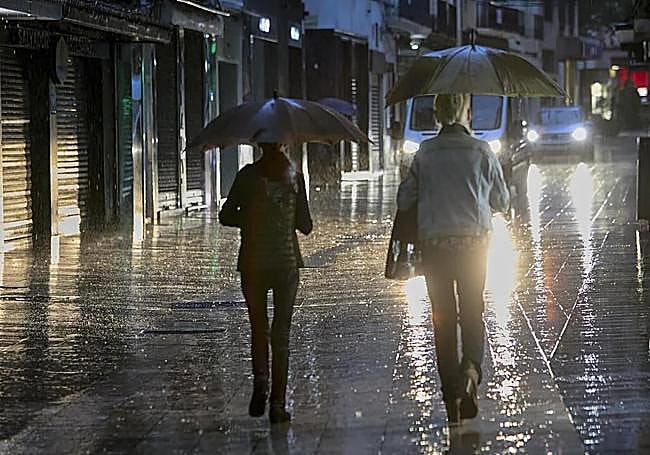 Dos personas pasean bajo la lluvia.